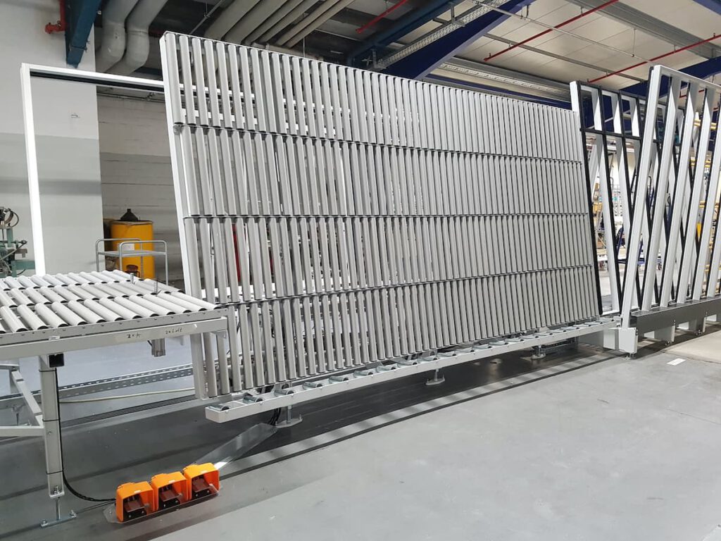 Automatisierte Produktionsanlage mit Förderband und vertikalen Riegeln, die in einer modernen Fabrikumgebung zu sehen sind. Die Struktur besteht aus Metall und ist für die effiziente Handhabung von Materialien konzipiert.