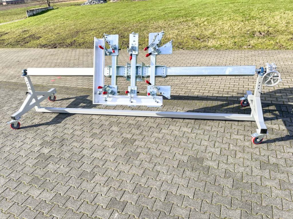 Mobiler Montagetisch mit verstellbaren Halterungen und Rollen, ideal für Bau- und Renovierungsarbeiten, auf einem gepflasterten Untergrund im Freien.